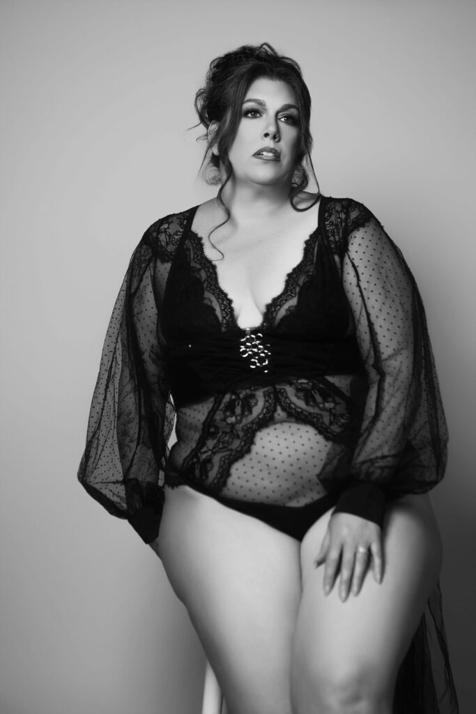 black and white ICON portrait of a woman wearing a black bodysuit sitting on a stool in front of a gray background in a maryland photography studio