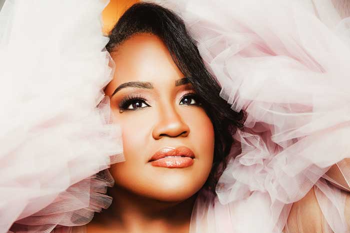 A close up portrait of a woman of color as she is surrounded by a big pink tulle robe